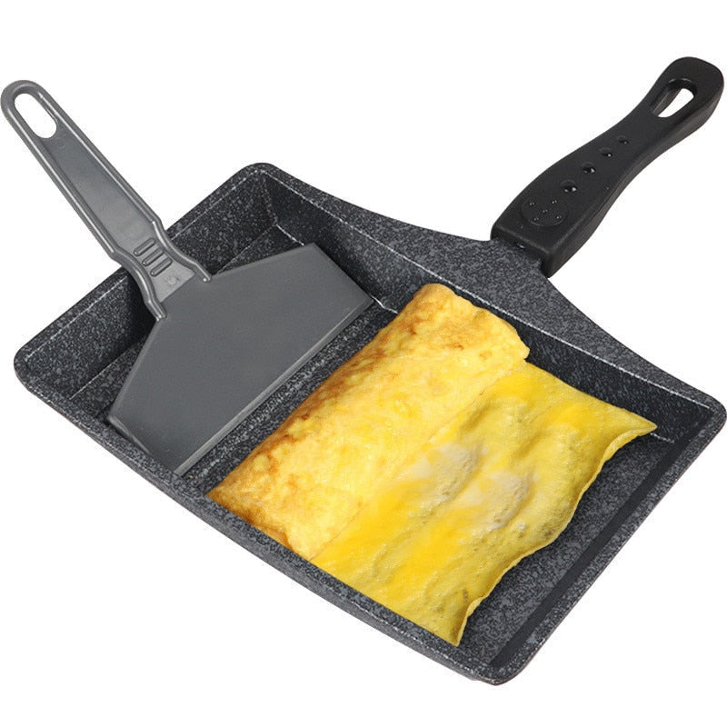 Non-stick wave bottom saucepan for tamagoyaki omelettes with spatula, black and beige.